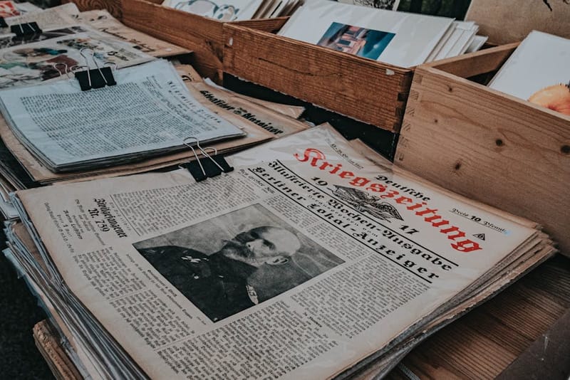 A folded newspaper alongside a fountain pen on a wooden desk