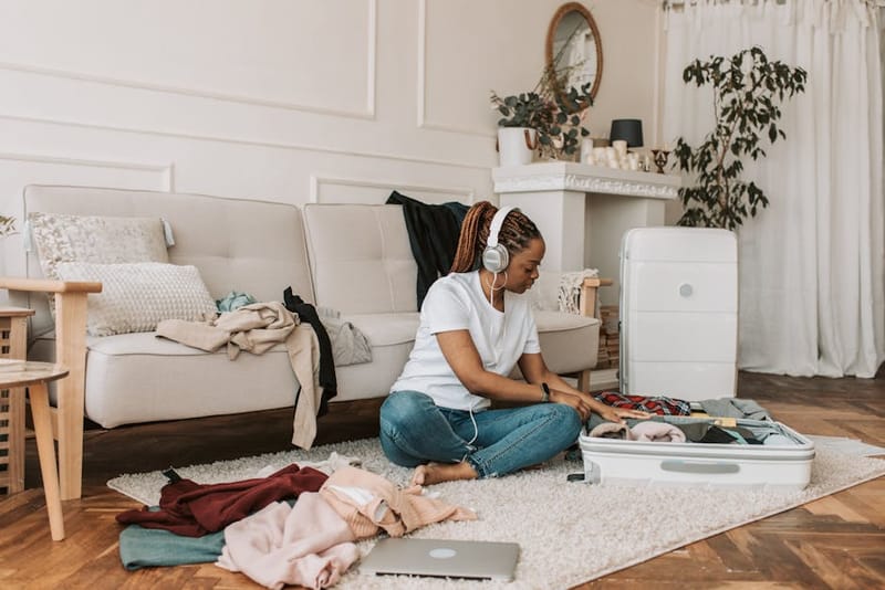 A packed suitcase and travel essentials laid out on a rug