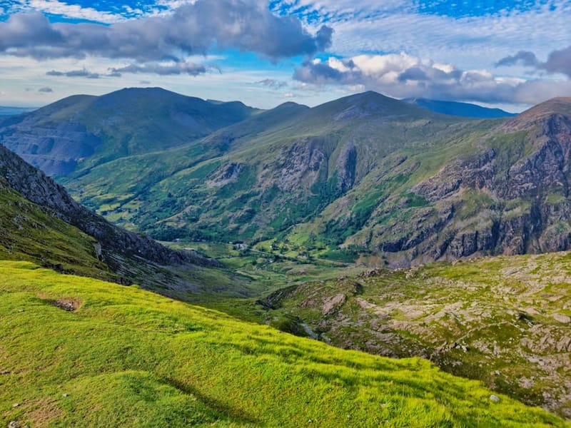 Breathtaking view of rugged mountains and green valleys under a vibrant blue sky.