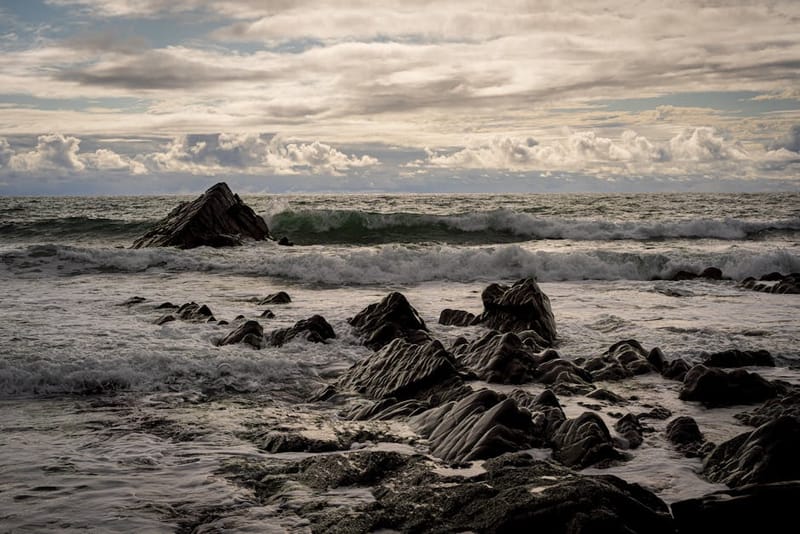 Captivating view of rugged rocks and ocean waves along Bude, Cornwall's coastline.