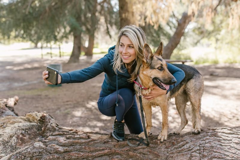 Dog owner using a smartphone app while walking a dog outdoors in the UK