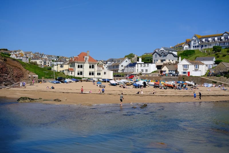 Relaxing summer day at Hope Cove beach with clear skies and vibrant seaside houses in England.