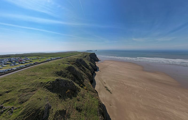 Stunning aerial view of Rhossili Bay's sandy beach and grassy cliffs in Wales.
