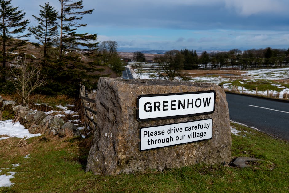 View of Greenhow village sign with a snowy countryside background, capturing winter serenity and rural charm.